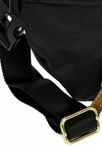 Borsa in tessuto nero con una texture intrecciata, dotata di una tracolla regolabile con hardware dorato e un dettaglio in pelle marrone per un tocco in più.