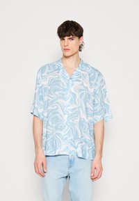 Camicetta manica corta di colore azzurro chiaro, con un motivo a marmo ondulato, realizzata in tessuto leggero con una vestibilità morbida e un colletto.