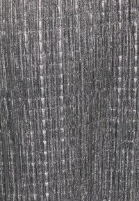 Gros plan d’un tissu gris texturé avec des lignes fines verticales et diagonales créant un motif tissé et un léger éclat.