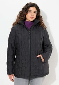 Svart puffjacka med dragkedja framtill, hög krage och strukturerad yta. Har två sidofickor och en något lös passform.