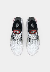 Witte en zwarte sportieve schoenen van mesh stof, met grijze accenten en een rode "CLIMACOOL" label. Voorzien van veters en gebogen zolen.