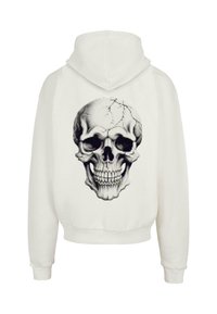 White hooded sweatshirt featuring a large black and gray skull graphic on the back, with a textured design and cracked details.