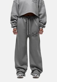 Grijze cropped sweatshirt met lange mouwen en een losse pasvorm, gecombineerd met bijpassende grijze sweatpants met een geborduurd detail op de dij.