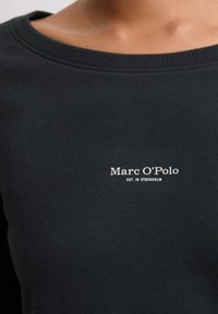 Felpa nera in cotone con scollo a girocollo e testo ricamato bianco "Marc O'Polo EST. A STOCCOLMA" sul davanti.