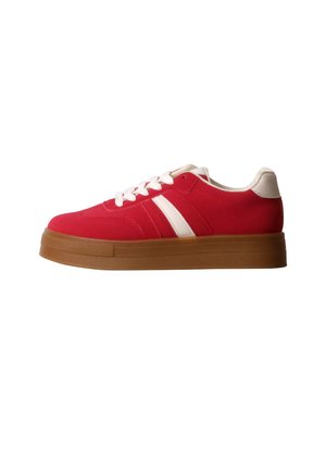 Basket basse rouge avec lacets blancs, bandes latérales blanches, languette de talon blanche et semelle épaisse en caoutchouc marron sur fond blanc.