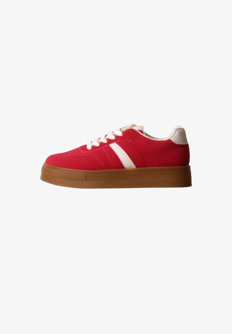 Basket basse rouge avec lacets blancs, bandes latérales blanches, languette de talon blanche et semelle épaisse en caoutchouc marron sur fond blanc.