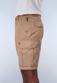 Bermudas beige de cargo con múltiples bolsillos, cierre con botón y detalles cosidos. Fabricadas con un tejido ligero para mayor comodidad y facilidad de movimiento.