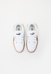 Ein Paar weiße Puma-Sneaker mit braunen Sohlen, weißen Schnürsenkeln und schwarzem Puma-Logo auf der Zunge, von oben auf einem weißen Hintergrund betrachtet.