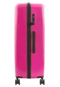 Hard-shell suitcase in vibrant pink with a glossy finish, black zipper, combination lock, side handle, and four wheels for mobility.