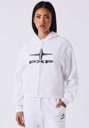 Haut de survêtement blanc cropped en tissu doux avec une fermeture éclair à l'avant, présentant un design de logo noir sur la poitrine et des poignets et ourlet côtelés.
