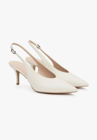 Bílé kožené podpatky s prstovým tvarem a umírněným podpatkem. Mají zakřivený výřez v designu a nastavitelné zpevnění kolem kotníku.