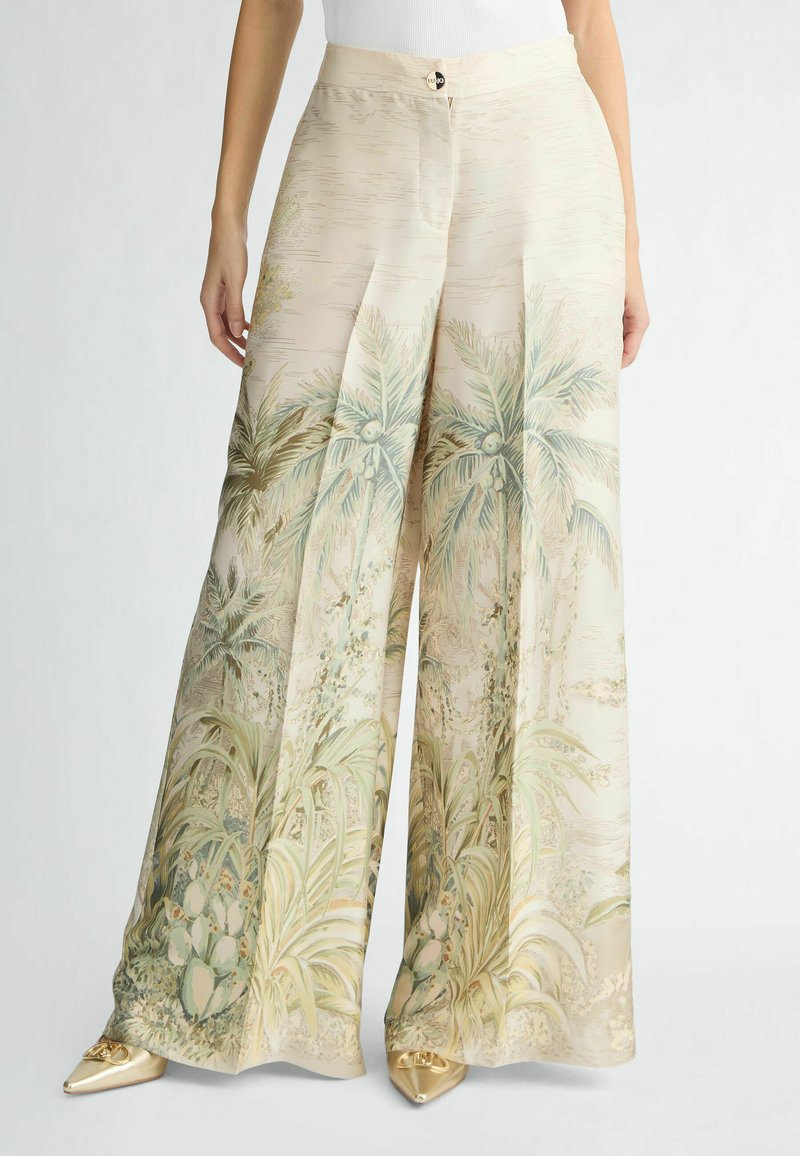 Wijdvallende broek van lichte stof in een zachte pastelkleurenpalet met botanische prints van palmbomen en cactussen; vooraan met knoopdetails.