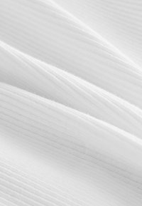 Tissu blanc avec une texture côtelée, présentant des plis doux et une subtile brillance. Le matériau semble léger et lisse.