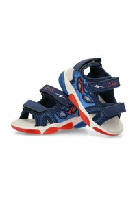 Sandalias infantiles en azul y marino con acentos rojos, que cuentan con punta cerrada, tiras de Velcro y una suela de goma texturada. Detalle de patrón de telaraña.