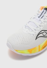 Zapatilla de running blanca con parte superior de malla, acentos reflectantes y suela en degradado de amarillo a naranja brillante. Presenta un cordón tradicional y detalles del logo.