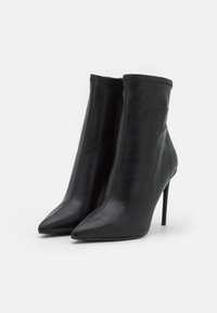 Zwarte leren enkellaarsjes met spitse neuzen en hoge stiletto-hakken, met een naadloos ontwerp en minimalistische stikseldetails.