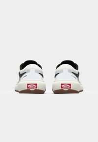 Białe i czarne trampki Vans z tyłu, z napisem "ULTRARANGE" po boku i "OFF THE WALL" na czerwonym oznaczeniu pięty. Gładkie tło.
