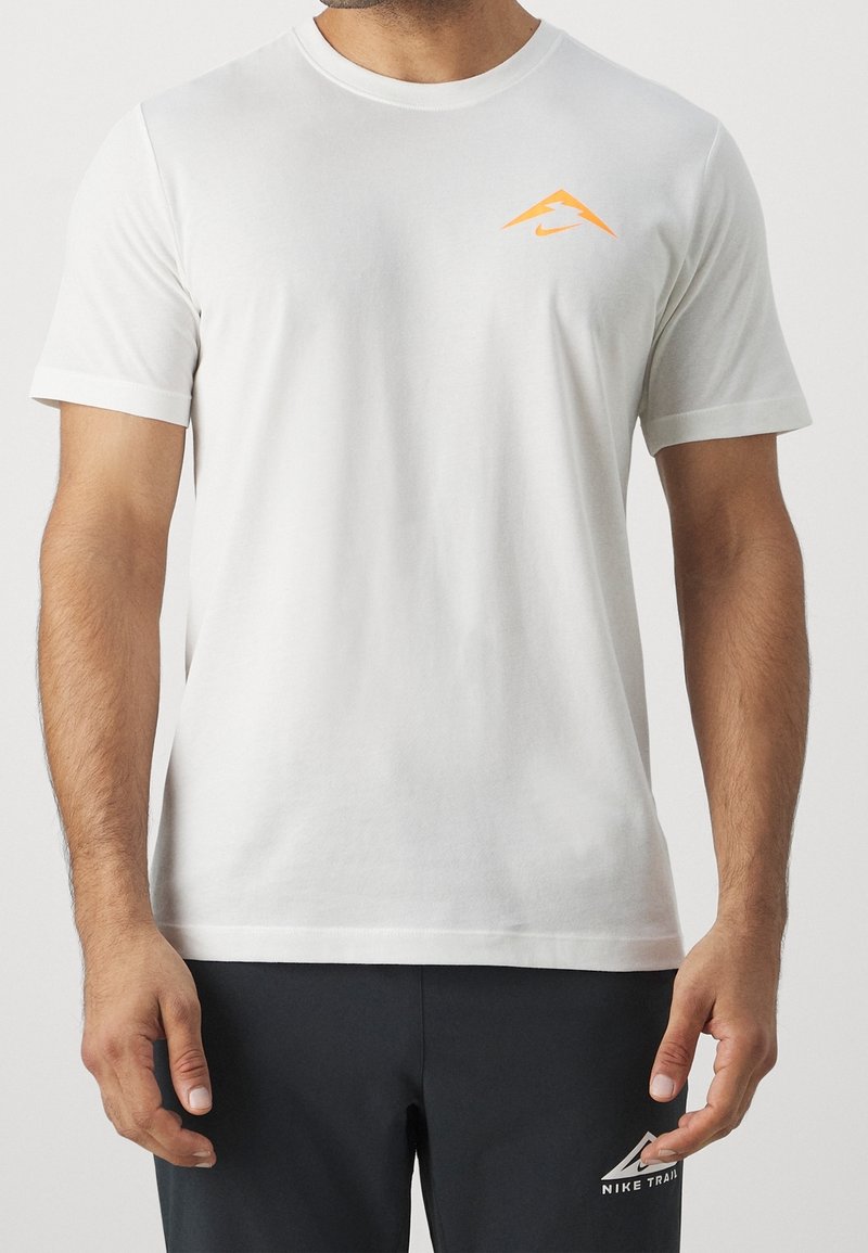 Camiseta de algodón blanca de manga corta, con un logo de Nike naranja en el pecho. Diseño sencillo, cuello redondo, textura suave.