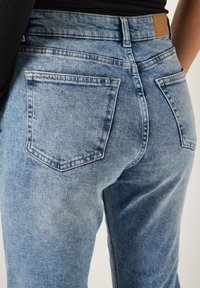 Lichtblauwe denim jeans met een klassiek vijfzakkenontwerp, een licht vervaagde textuur en een bruine leren patch op de tailleband.