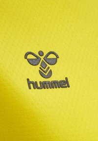 Ljust gult tyg med en texturerad yta. En mörkgrå "hummel"-logotyp och en stiliserad bidesign är tydligt synliga.