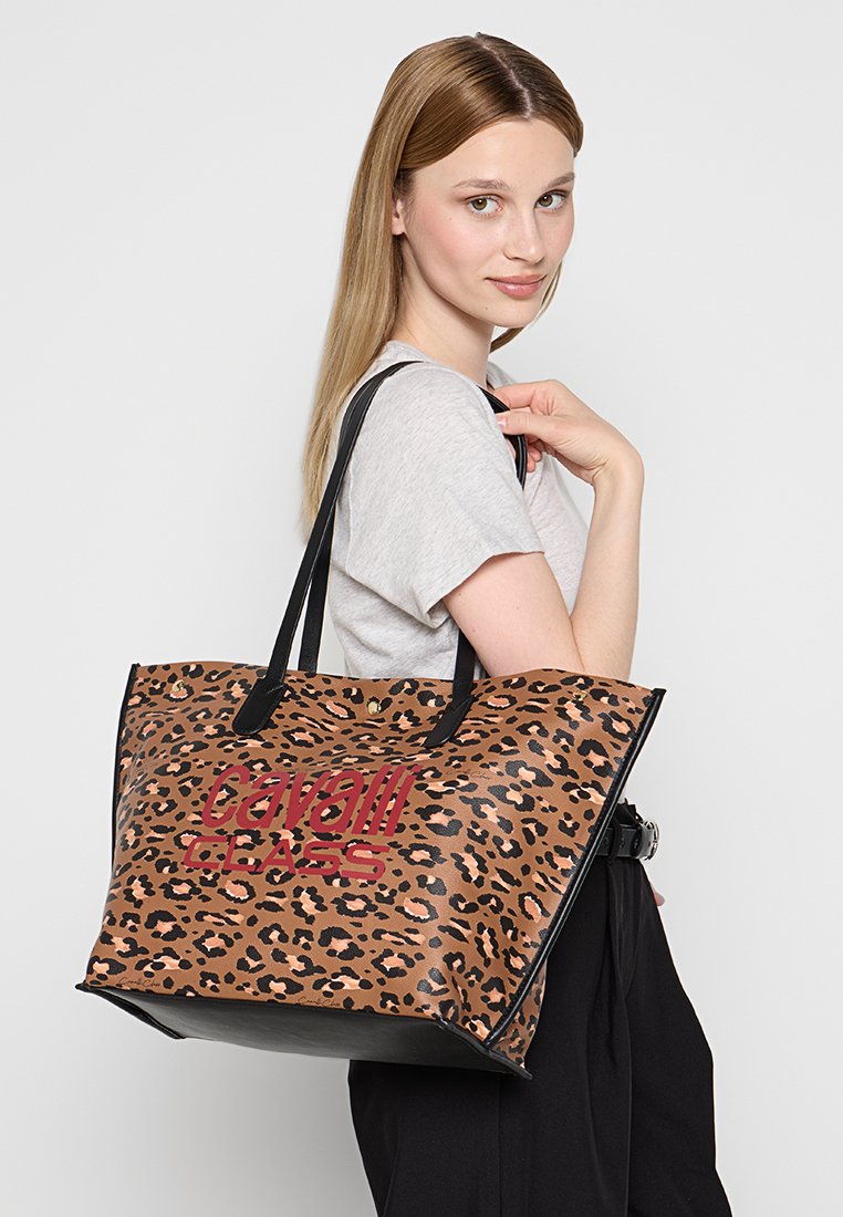 Torebka tote w wzór panterki wykonana z materiału syntetycznego, z czarnymi akcentami i wypukłym logo "Cavalli Class" w kolorze czerwonym. Duży, usztywniony fason.
