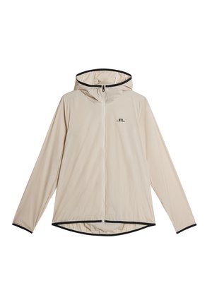 Beige lättviktjacka med huva, svart dragkedja och kant. Slät textur, långa ärmar, lätt böjd nederkant, har logotyp på vänster bröst.