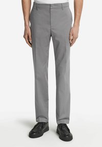 Grå byxor i en slät väv, med rak bendesign, bältesloopar och slät front, i kombination med svarta skor.