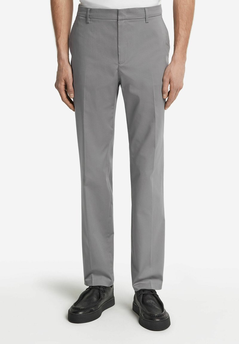 Grå byxor i en slät väv, med rak bendesign, bältesloopar och slät front, i kombination med svarta skor.