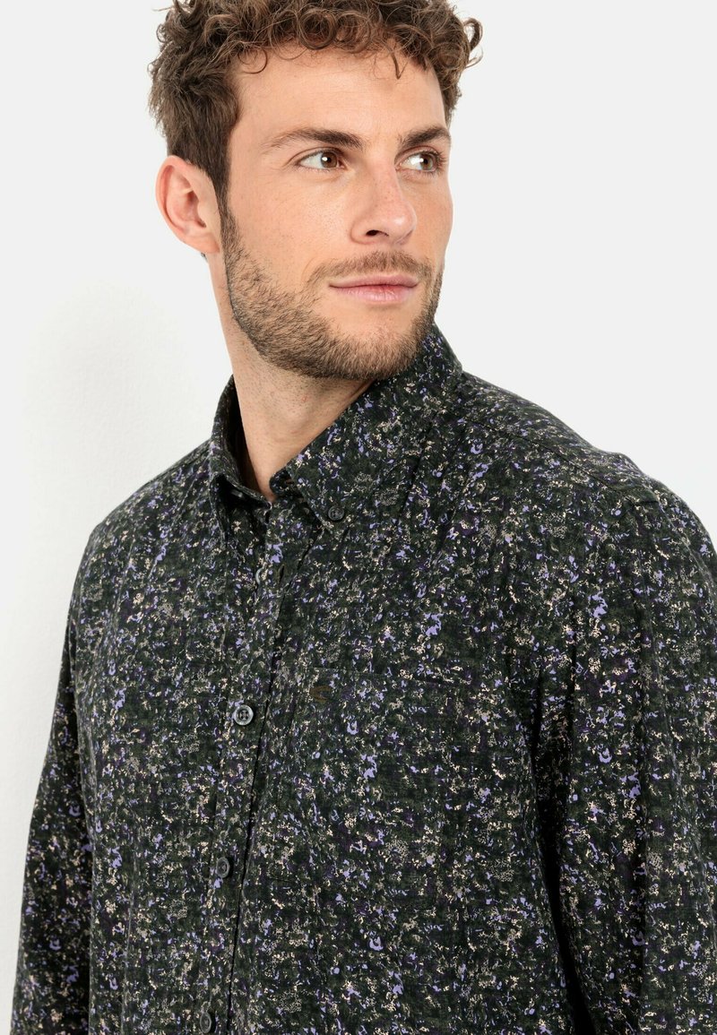 Ein dunkelgrünes Button-up-Hemd aus Stoff mit lila und goldenen Blumenmustern, ausgestattet mit einem strukturierten Kragen und Einknopf-Manschetten.