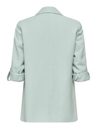Blazer décontracté vert clair avec manches retroussées vu de dos, avec un col cranté et un ourlet droit.