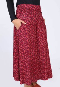 Roter Blumen-Maxi-Rock mit gerafftem Taillengummi, seitlichen Taschen und einem fließenden Schnitt aus weichem Stoff.