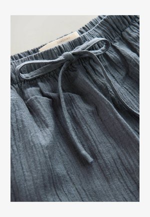 Grau melierte Shorts mit elastischem Bund und einer vorderen Kordel zum Binden. In der Nähe des Bundes befindet sich ein Etikett mit der Aufschrift "CONTAINS".