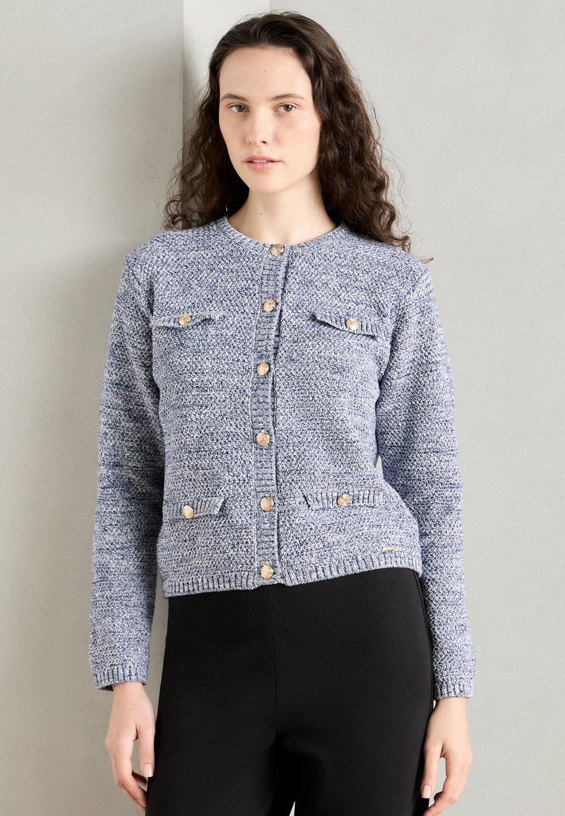 Blue knit cardigan with gold buttons, two front pockets, and ribbed cuffs and hem. Textured fabric with a subtle pattern.