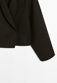 Czarna krótka kurtka wykonana z miękkiej tkaniny, z kołnierzem z klapą, długimi rękawami i ogólnie gładką fakturą.