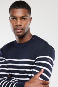 Mørkeblå og hvidstribet sweater lavet af strikket stof, med knapdetaljer på skulderen og et mærke på ærmet.