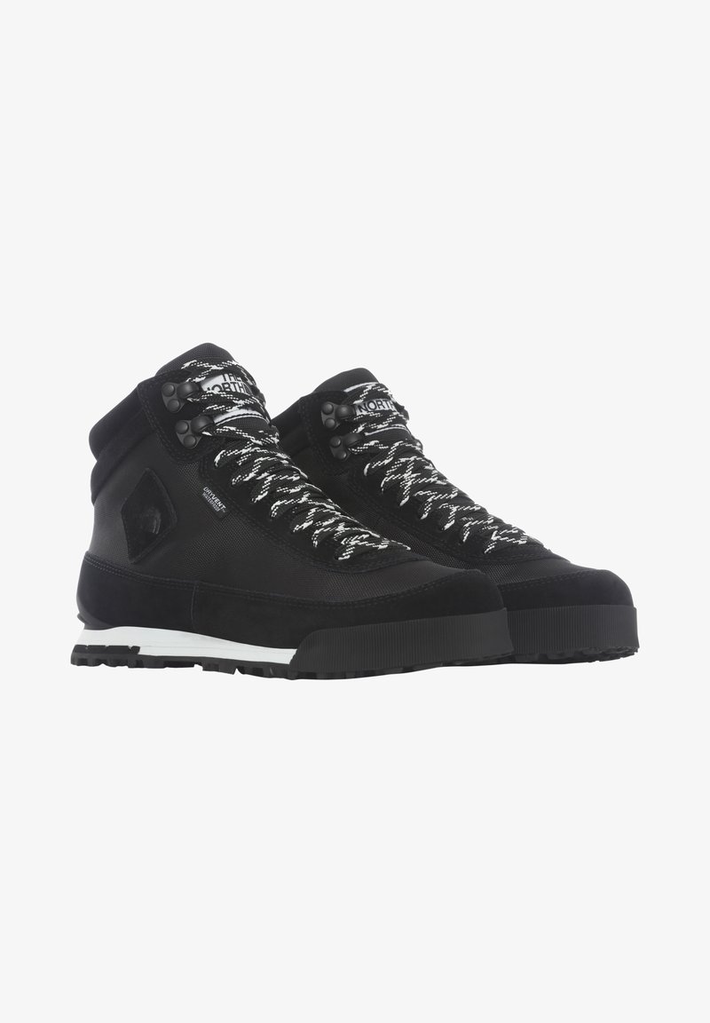 Paire de bottes de randonnée montantes noires avec des lacets blancs à motifs, des semelles robustes et un logo de marque sur le côté et la languette.
