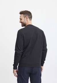 Felpa nera con maniche lunghe e collo a giro, caratterizzata da una vestibilità comoda e polsini e orlo a costine. Tessuto liscio con dettagli minimi.