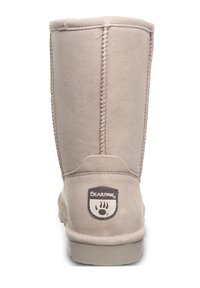 Hellbraune Wildleder-Stiefel in Knielänge mit dekorativem Stich und flacher Gummisohle. Mit einem Bearpaw-Logo-Patch auf der Rückseite.