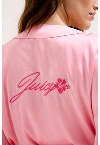 Robe en satin rose ornée du texte brodé "Juicy" et d'un motif de fleur d'hibiscus au dos. Texture douce et style col classique.