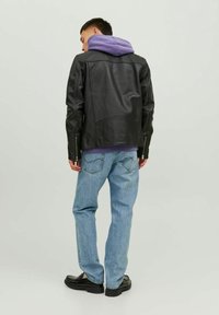 Svart läderjacka med bakseams, kombinerad med en lila huva sweatshirt och ljusblå denimjeans, bärs med svarta skor.