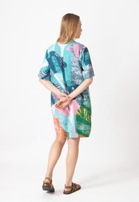 Lyhythihainen mekko, jossa on värikäs abstrakti kuvio teal, vaaleanpunaisen, vihreän ja oranssin sävyissä. Valmistettu kevyestä kankaasta rentoa istuvuutta varten.