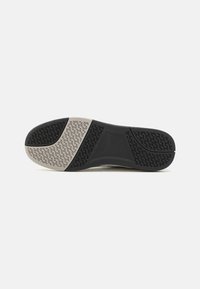 Shoe sole with a textured pattern. Black rubber at toe and heel, light gray midsole with patterned grip for traction. Smooth surface overall.