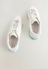 Weiße Sneakers mit mehrfarbigen Akzenten, einschließlich einer durchsichtigen Sohle und verspielten Charms an den Schnürsenkeln. Glattes Material, rundes Zehendesign.