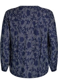 Blouse marine avec un motif floral en blanc ; manches longues avec des poignets élastiques ; col rond ; tissu léger avec une texture douce.