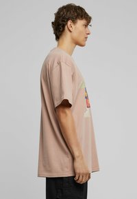 Light pink cotton t-shirt featuring a colorful graphic design on the front. Short sleeves, loose fit, and standard crew neckline.