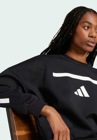 Black sweatshirt made of cotton blend, featuring a white horizontal stripe and logo on the chest, with ribbed cuffs and a relaxed fit.