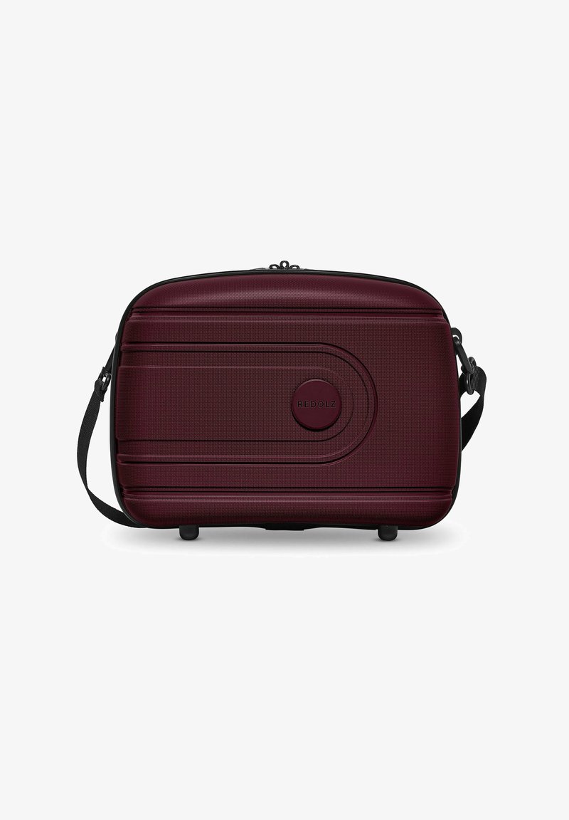 Rode koffer, diep bordeauxrood, gestructureerd oppervlak, ronde vorm, ritssluiting, verstelbare schouderband, gemarkeerde ronde accent aan de voorkant.