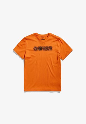T-shirt orange vif à manches courtes avec le texte noir usé "RAW STAR" sur la poitrine, posé à plat sur un fond blanc.