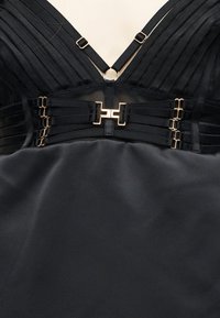 Schwarzes Satin-Kleid-Oberteil mit gerippten Stoff-Cups, goldfarbenen Metallringen, verstellbaren Trägern und dekorativen Seitenriemen mit Haken.