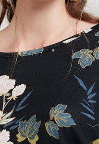 Top in tessuto nero con motivo floreale nei toni di rosa, giallo e blu, caratterizzato da un'ampia scollatura e texture a coste.